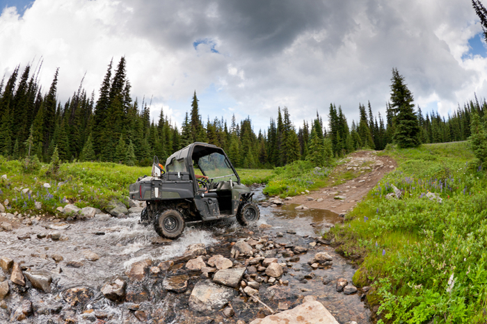 An ANSI/OPEI B71.9 multipurpose off-highway utility vehicle crossing a forest creek.
