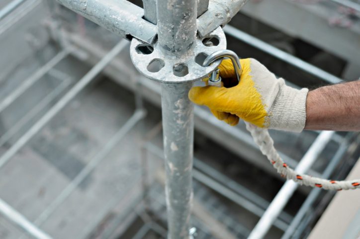 Worker locking in caribener to not violate fall protection OSHA requirements.