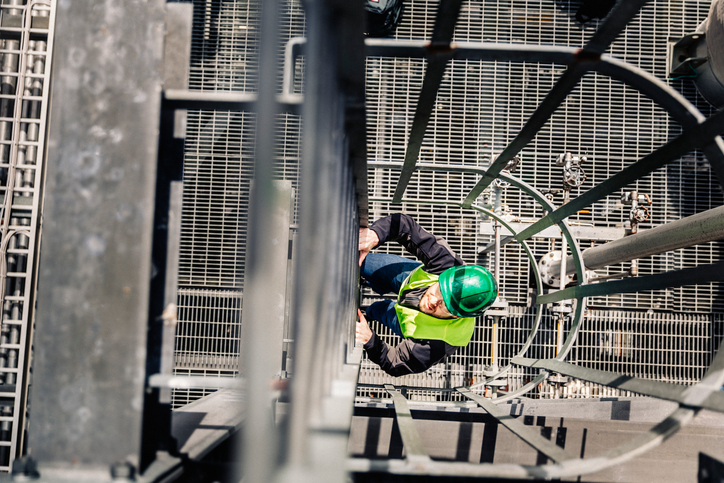 Man climbing a caged ladder while donning ANSI/ISEA 107-2020 High-Visibility Safety Apparel.
