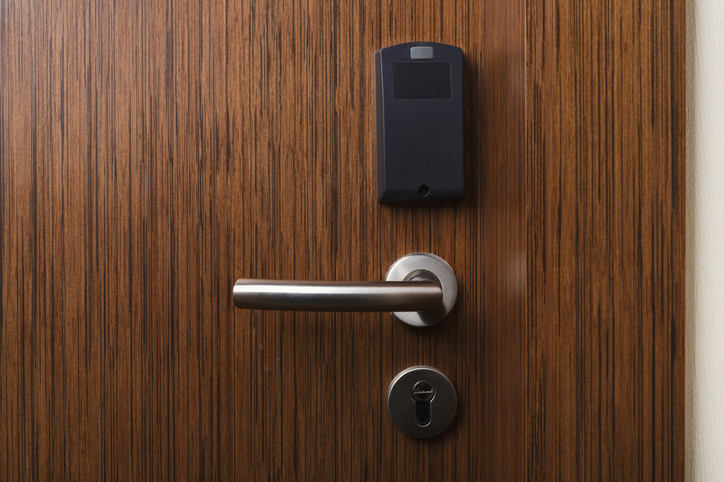 At a hotel, a brown door contains a secure ANSI/BHMA A156.23-2017 electromagnetic lock to lead into room.