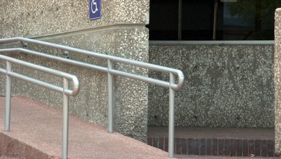 A ramp with metal railings shows the errata to ICC A117.1 2017 for accessible buildings corrections.