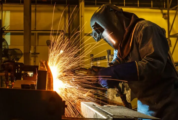 A welder following AWS D17.1M and safety practices with flying sparks.