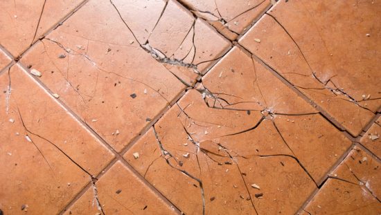 Tan ceramic tiles have been cracked and destroyed after an impact falling steel ball ASTM C1870 test.