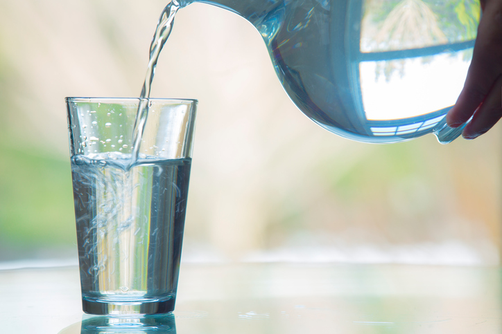 Cryptosporidium-free water being poured from pitcher into clear glass.