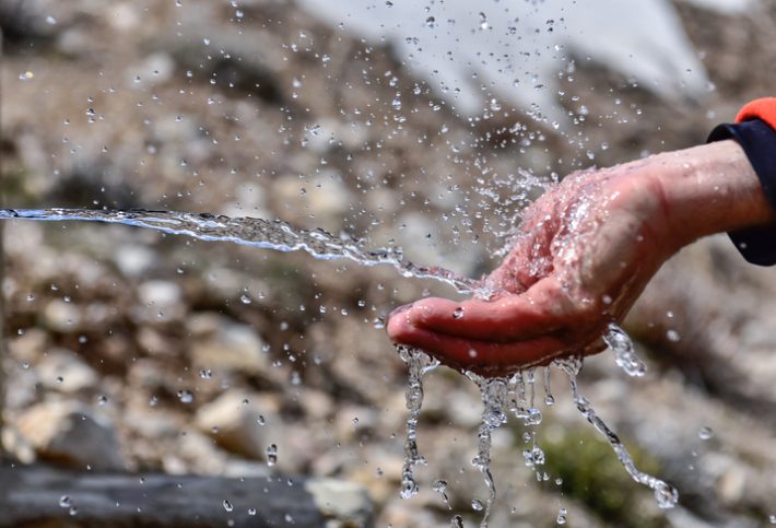 Clean drinking water spurting into cupped hands.