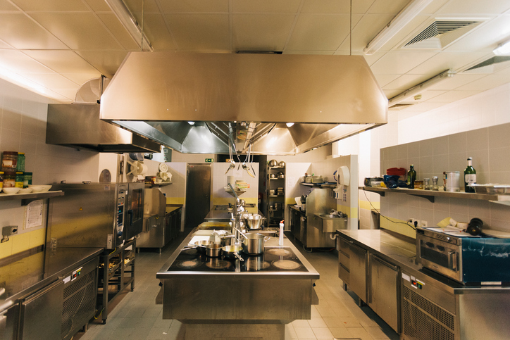 A dark empty kitchen with a chrome exhaust system cleaned to ANSI/IKECA C10-2021.