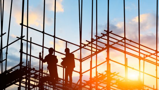 Two workers on a construction site that follows the safety guidelines of NFPA 241-2019