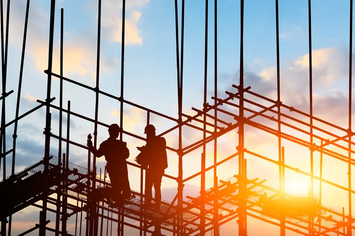 Two workers on a construction site that follows the safety guidelines of NFPA 241-2019