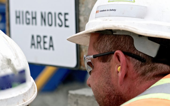 Construction manager with yellow earplugs blocking ASME PTC 36-2018 industrial noise.