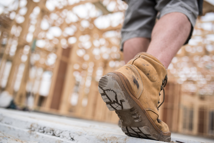 Man walking in protected construction site with brown ASTM F2412-18 tested boots.