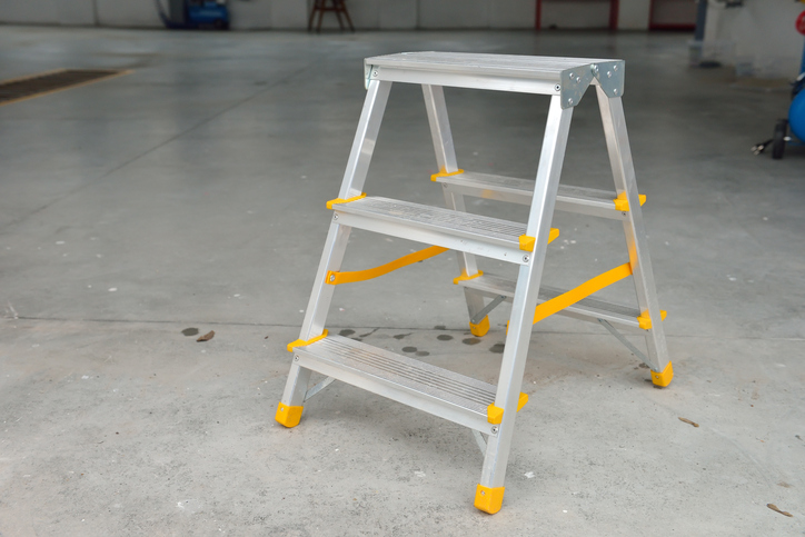 A metal ASC A14.11-2018 stepladder with bright yellow plastic marking safe spots.