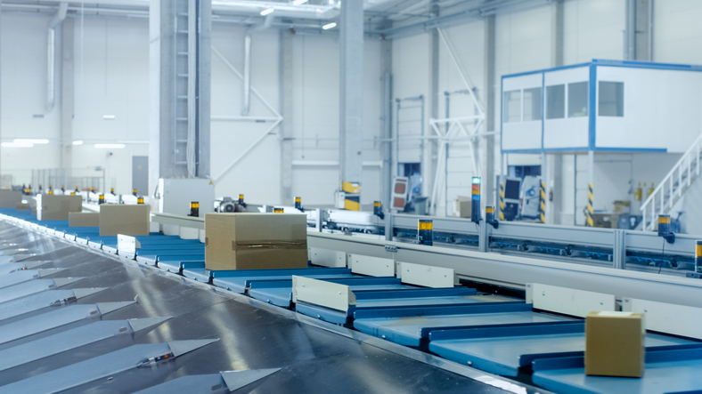 Blue conveyor shuttling boxes and kept safe thanks to ASME B20.1-2021.