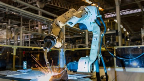 An industrial robot arm safely welds an automobile in an automated factory.