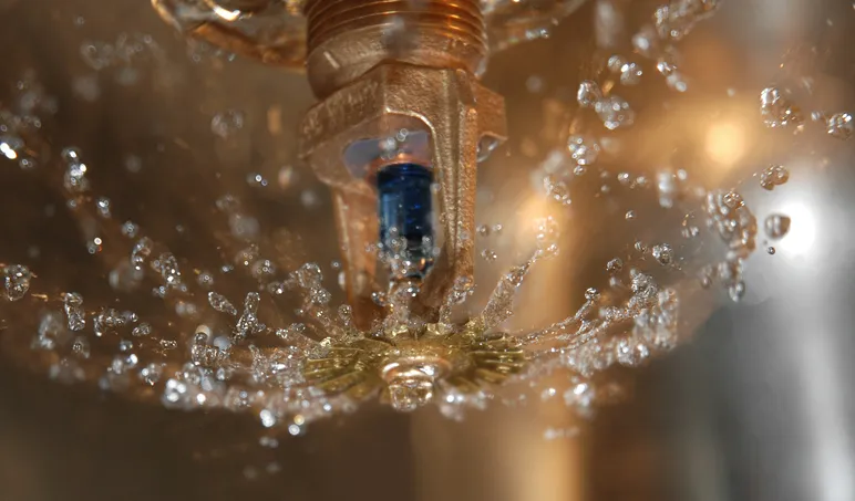 An indoor sprinkler with water coming out of it that is following NFPA 25-2020