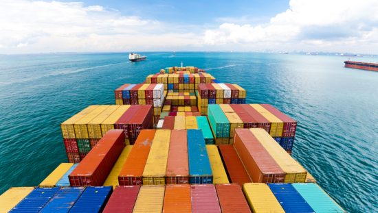 Series 1 freight containers following ISO 668:2020 and piled on barge at blue sea.
