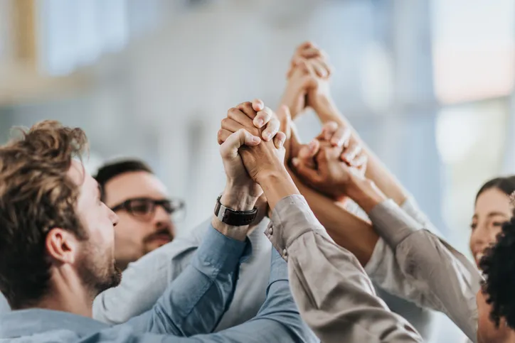Coworkers holding each other's hands raised in the air to show resilience