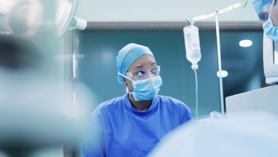 Woman in an operating room with personal protective equipment on that is specified in ANSI/AAMI PB70:2012