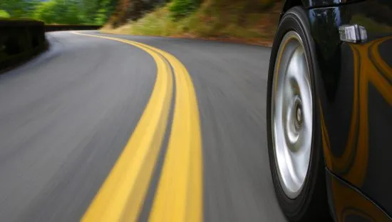 Black sports car speeds in landscape that blurs like a painting with wheels tested to SAE J 175-2020 for lateral impact