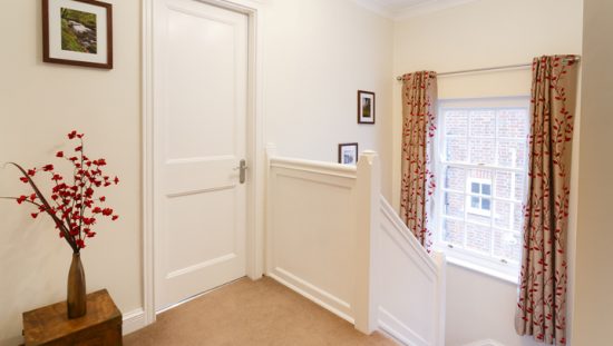 Upstairs landing in a house, next to a closed bedroom door