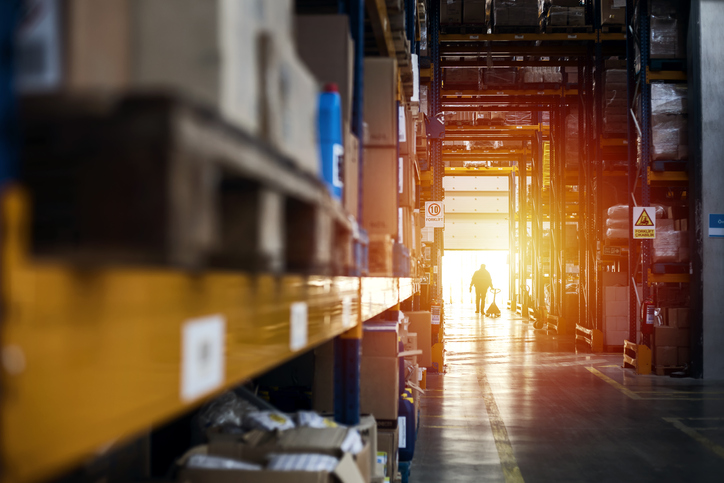 Man walking from warehouse interior at sunset after following ANSI/ITSDF B56.1-2020 for forklifts and trucks