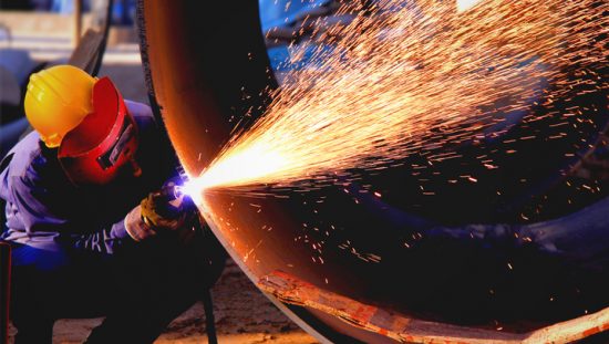 Welder shooting sparks while working on steel pipeline flanges with ANSI/MSS SP-44-2019