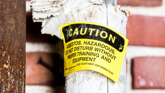 Yellow asbestos warning on broken pipe than cannot be ignored when properly removing and disposing during construction.