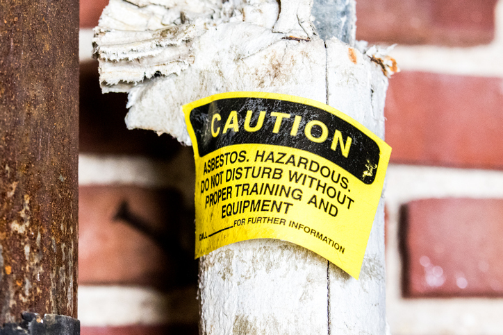 Yellow asbestos warning on broken pipe than cannot be ignored when properly removing and disposing during construction.