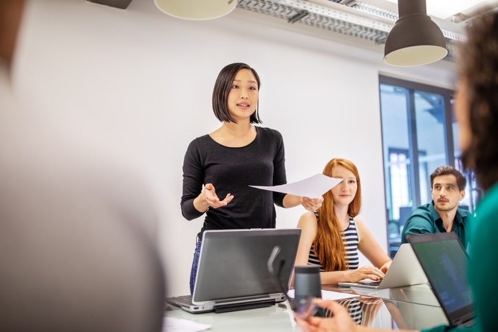 Company Meeting Confident female leader discusses the advantages of leadership following an ISO 9001 quality management system.