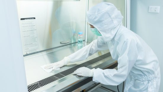 Scientist wearing protective clothing and wiping down biosafety cabinet, struggling with common lab decontamination.