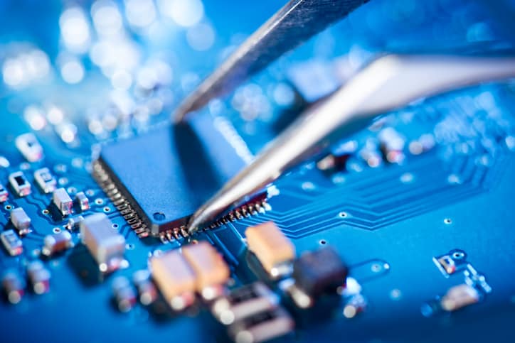 Blue circuit board being checked via IPC A-610H-2020 acceptability of electronic assemblies defect and problem testing.