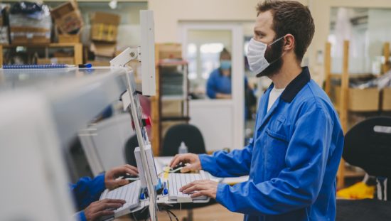 Masked engineer getting hands-on experience in the ANAB Industry-Recognized Apprenticeship Program (IRAP).