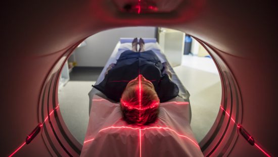 Patient undergoes red light of PET scan and CAT scan technology refurbished to IEC 63077 medical imaging requirements.