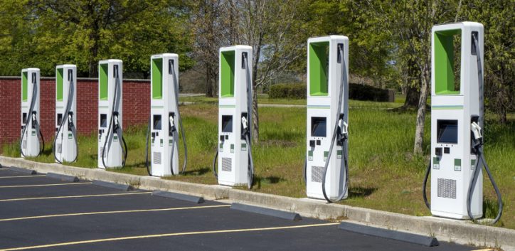 Green electric vehicle charging stations lined up in mall parking lot in IEC 61851 adherence.