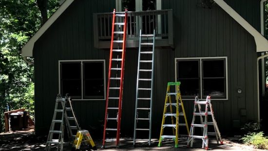 Ladders leaning against a cabin in the woods during National Ladder Safety Month