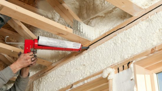 Worker caulks gap in home to mitigate radon entry in accordance with ANSI/AARST standards.
