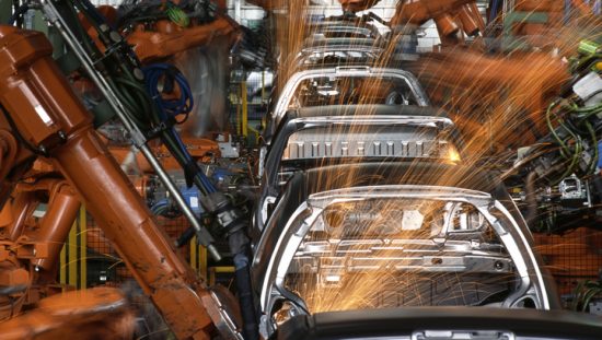 Robot arms manufacturing automobiles in compliance with IATF 16949 and ANAB accredited laboratories.