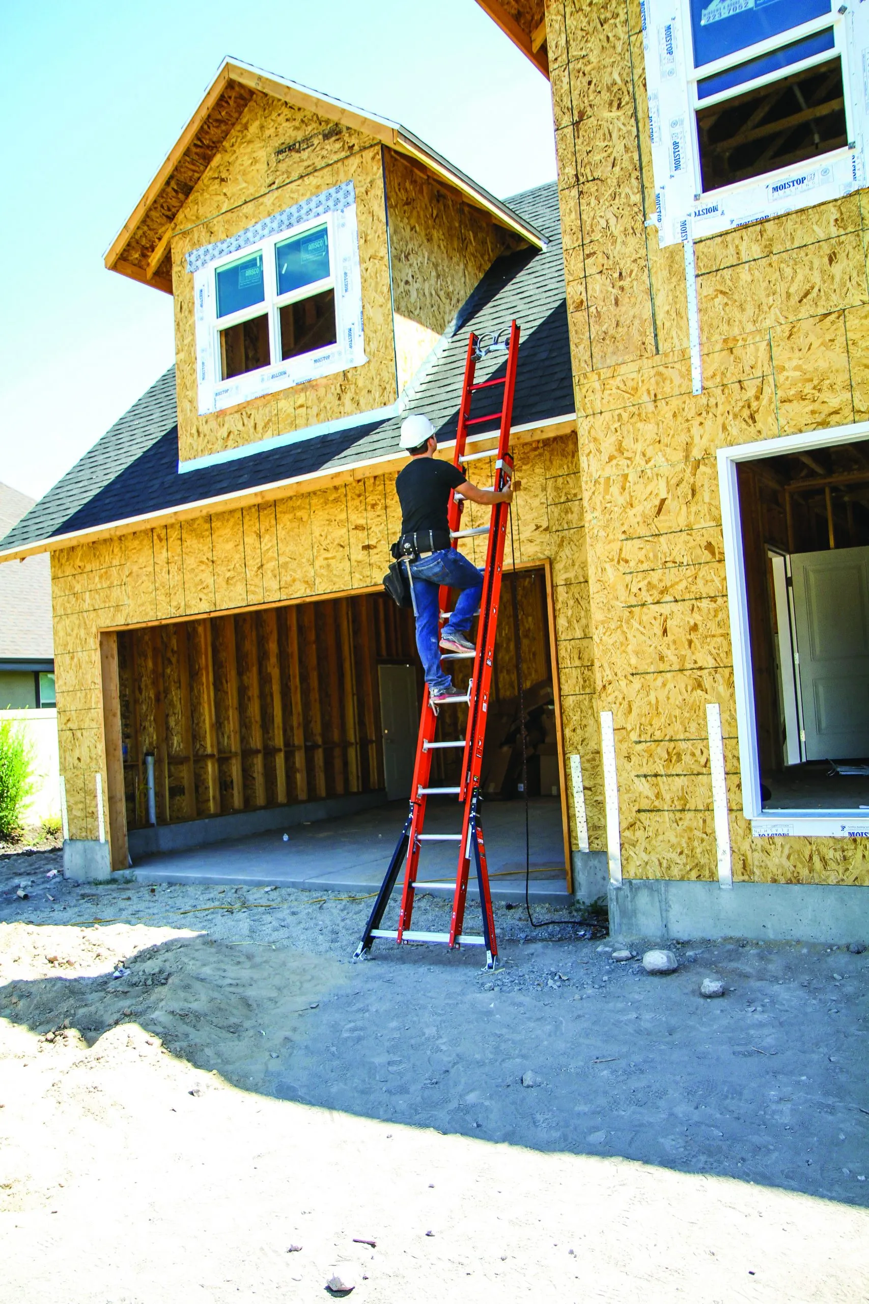 Construction worker climbing red metal extension ladder with three points of contact and basic safety tips.