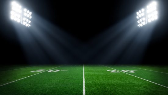 Verdant football field at night with stadium lights set properly with ANSI/IES RP-5-21 illumination.
