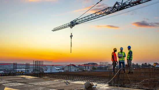 Construction workers in HVSA discussing the 2020 OSHA Top 10 List of Cited Violations under sunset crane.