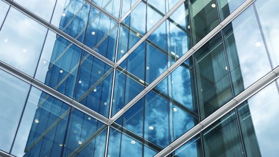 Flat glass exterior of blue corporate building that has been quality tested to ASTM C1036-21.