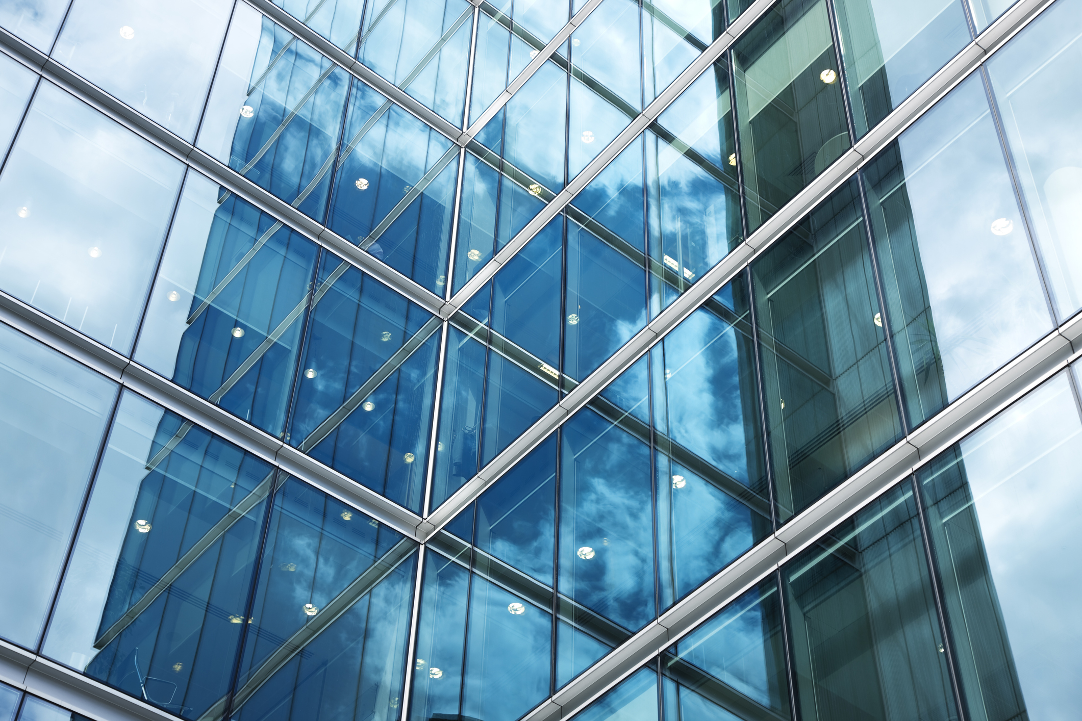 Flat glass exterior of blue corporate building that has been quality tested to ASTM C1036-21.