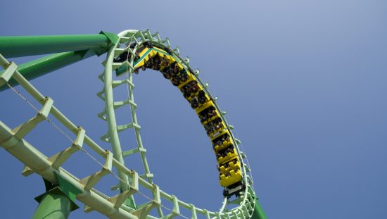 Green roller coaster loop providing ASTM F2291-21 amusement ride patrons with safe thrills.