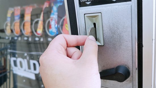 Patron inserting a quarter into an NSF/ANSI 25-2021 tested safe food vending machine.