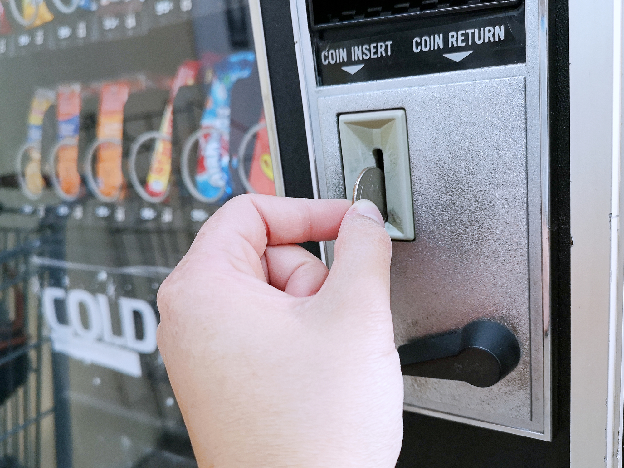 Drinks Patron inserting a quarter into an NSF/ANSI 25-2021 tested safe food vending machine.