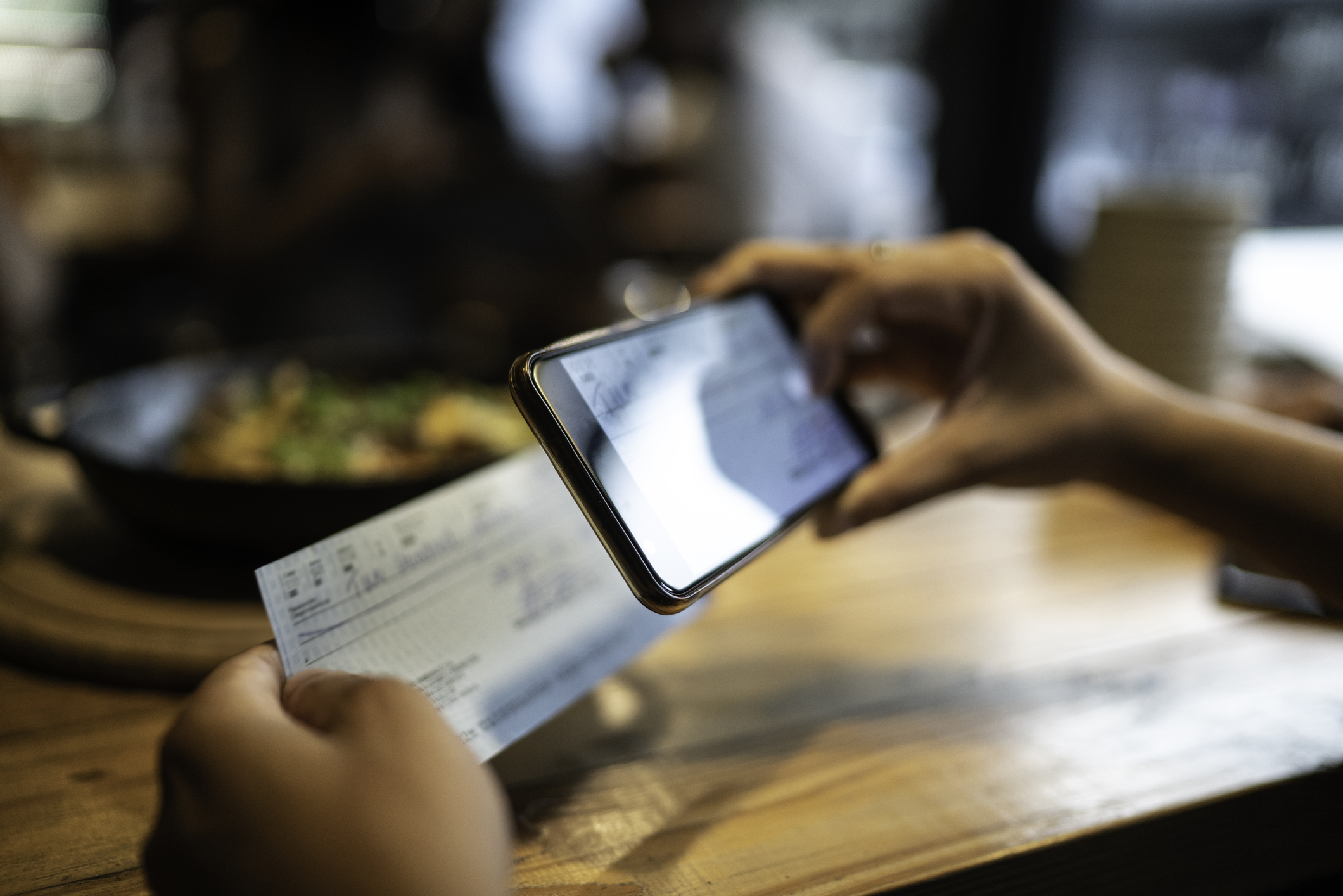 Signing Check Man making mobile check deposit through app assured with ANSI X9.100-187-2021 provisions.